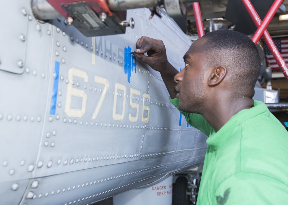 USS Lake Erie (CG 70) AM2 prepares to paint an MH-60R Sea Hawk