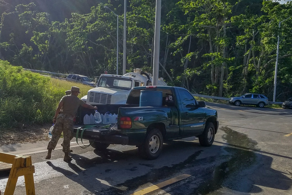 Soldier Loads Water Jugs into Pickup