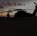 Soldier walks away from helicopter at sunset