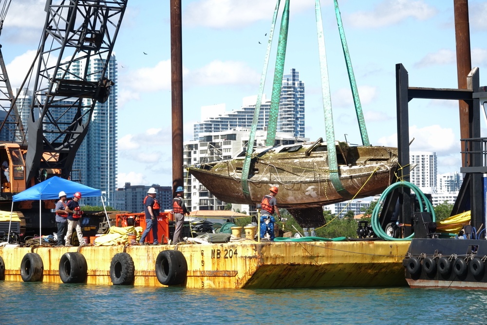 crews secure a sailing vessel on a barge