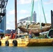 crews secure a sailing vessel on a barge