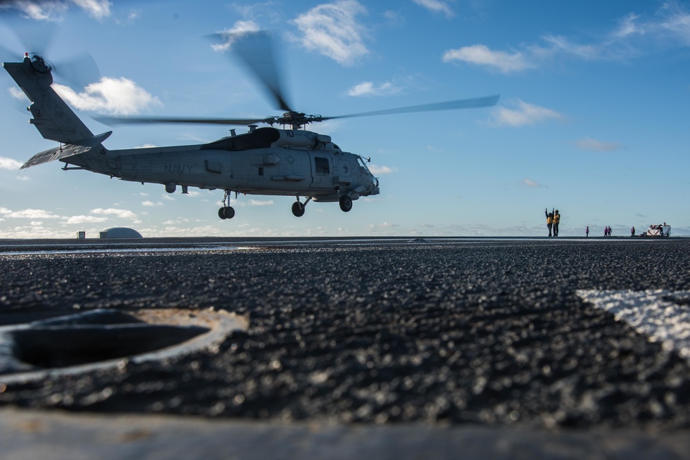 Sailor guides the lift off of a helicopter.