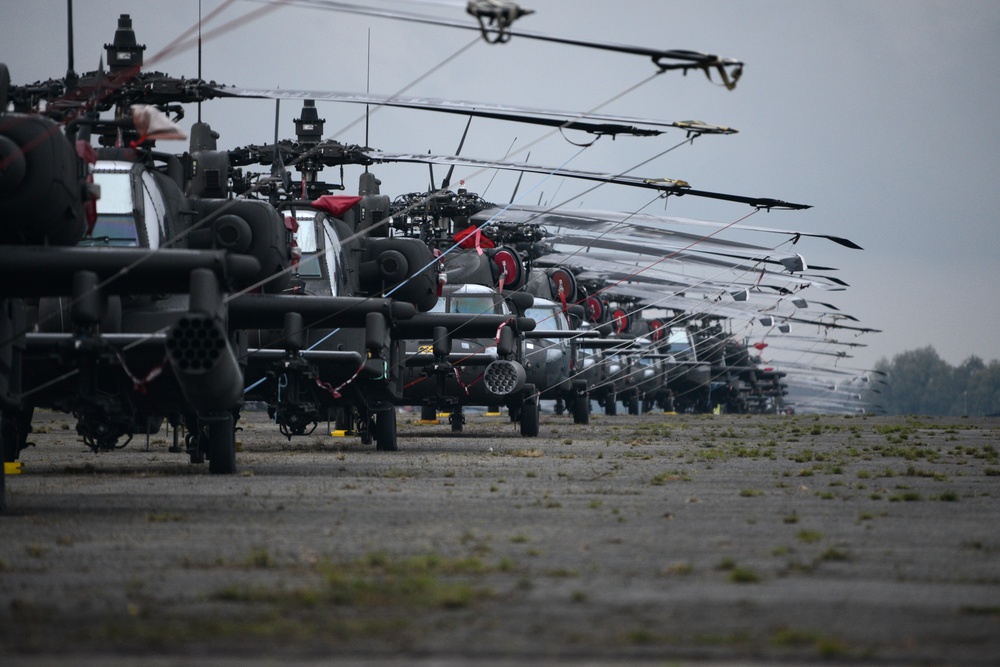 Black Hawk, Apache, and Chinook helicopters lined up on flight line. 