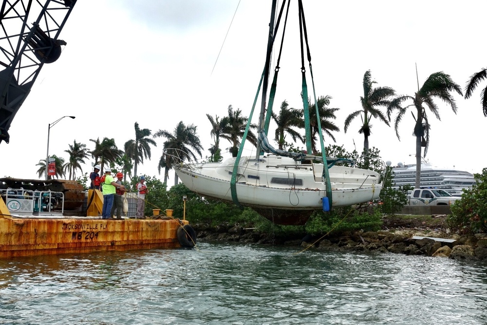 Response crews lift a sailing vessel from the water along the MacArthur Causeway