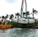 Response crews lift a sailing vessel from the water along the MacArthur Causeway