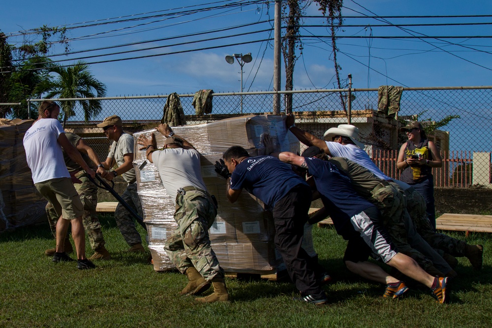 Soldiers and Volunteers Push Pallet of Grocery Boxes