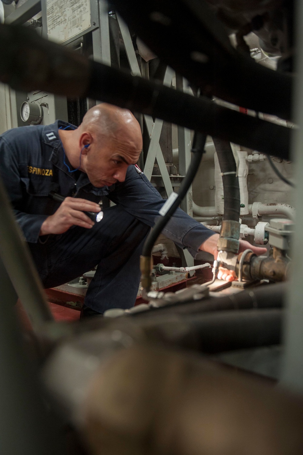 USS America Sailor inspects engine space for water leaks