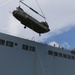 1st Armored Division Combat Aviation Brigade soldiers and USNS Brittin sailors load Chinook helicopters by crane in Ponce