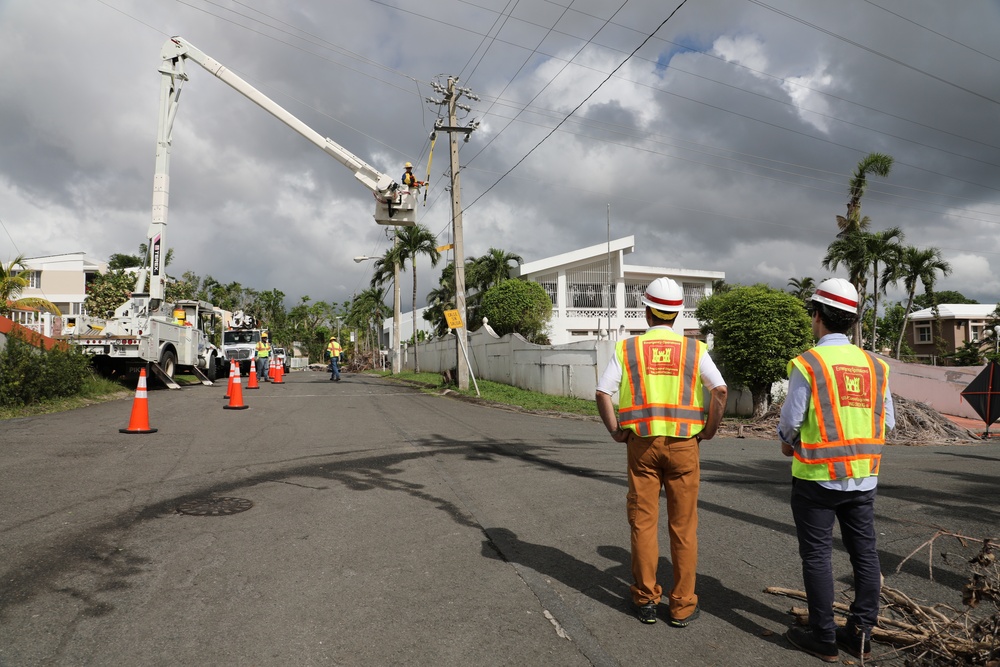 Work is completed on a power line while two U.S. Army Corps of Engineers employees observe
