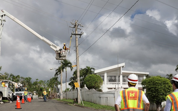 Work is completed on a power line while two U.S. Army Corps of Engineers employees observe
