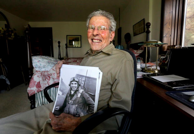 Frank McCauley smiles and holds a portrait of him in his younger years. The ace pilot passed away at 100 years old. (Courtesy photo by Perry Backus)
