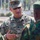 A U.S. Army soldier identified by name tape as 'Montemayor' is engaged in conversation with foreign military personnel wearing distinctive green berets and camouflage uniforms of a different pattern. The U.S. soldier wears OCP (Operational Camouflage Pattern) uniform with a major's oak leaf cluster rank insignia visible on the chest. The setting appears to be an outdoor military installation, suggesting an international military engagement or liaison activity.