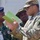 The image shows a group of military personnel engaged in what appears to be a briefing or discussion. A soldier in US Army MultiCam (OCP) uniform is holding a green notebook and appears to be explaining something to officers wearing Nigerian Army uniforms. The interaction suggests a joint military cooperation or training event between US and Nigerian armed forces.