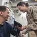 USS America Sailor checks patient’s vital signs