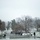 First Snow of the Season at Arlington National Cemetery A snow-covered cemetery, consistent in appearance with Arlington National Cemetery, photographed on an overcast winter day. Rows of white grave markers are visible across the grounds, partially dusted with snow. Several visitors are walking along pathways through the cemetery despite the cold, wet conditions.