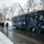 First Snow of the Season at Arlington National Cemetery A navy blue trolley bus operated by Arlington National Cemetery Tours is parked on a wet, snow-dusted road. Four visitors dressed in winter clothing are walking alongside the trolley on a cold, overcast day. The scene takes place within or near Arlington National Cemetery, as indicated by the branding on the vehicle.