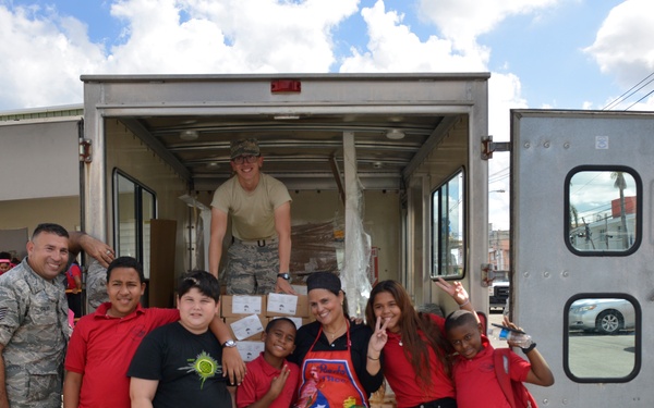 Airmen from the 156th Airlift Wing distribute food to local area children’s schools