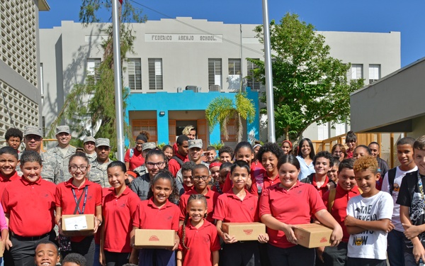 Airmen from the 156th Airlift Wing distribute food to local area children’s schools
