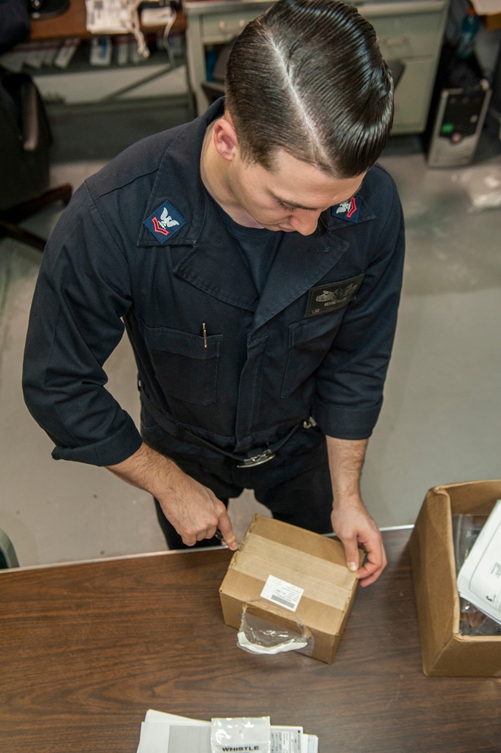 USS AMerica Sailor opens packages to inventory