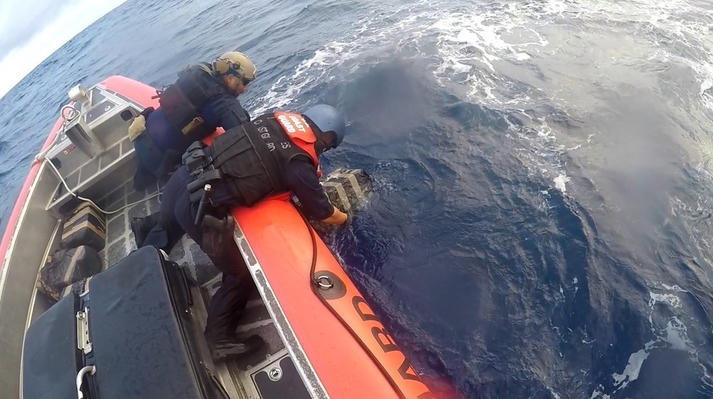 Coast Guard boat crew pulls bales of cocaine from the water