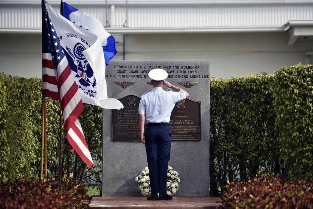Coast Guard Air Station Miami crew member salutes after laying a wreath at memorial remembrance ceremony