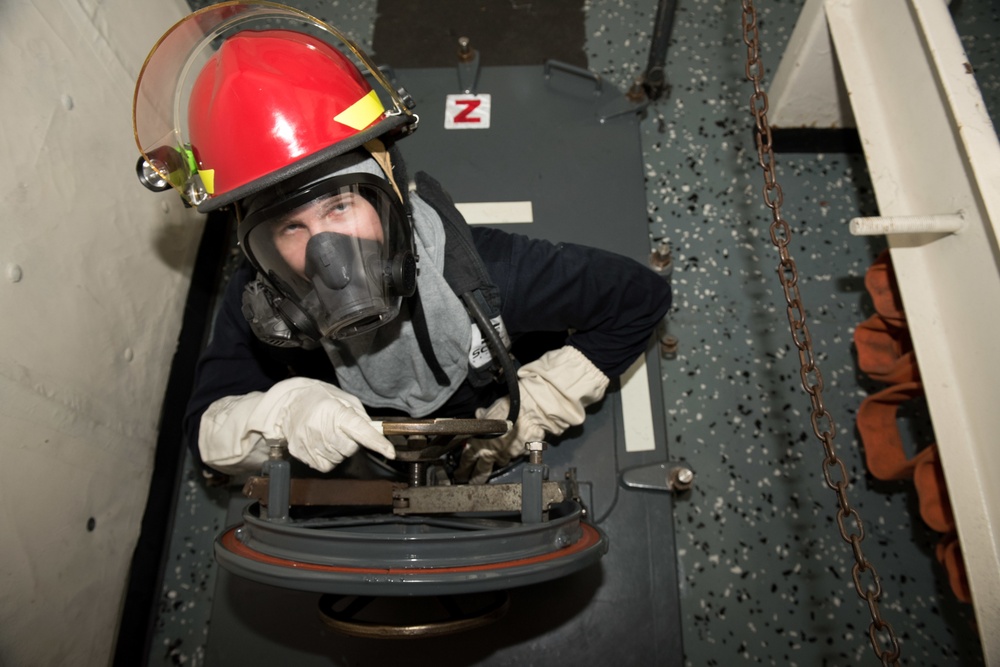 Sailor climbs through a scuttle during general quarters