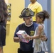 Firefighter Hands Gift to Little Girl at the Grand Three King's Celebration