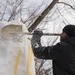 Sailor carves snow from sculpture