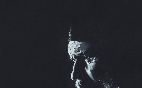 A dramatic, high-contrast black and white portrait — appearing to be a detailed drawing or artwork — depicting an elderly bearded man in profile view against a near-black background. The subject wears a wrapped head covering (turban) and has a long white beard, with selective lighting illuminating his facial features. A signature and date ('2015') are visible in the lower right corner, confirming this is an original artwork.