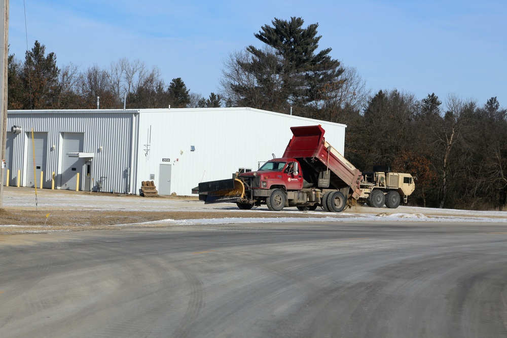 Snow-removal contractor covers icy area with sand at Fort McCoy
