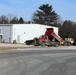 Snow-removal contractor covers icy area with sand at Fort McCoy