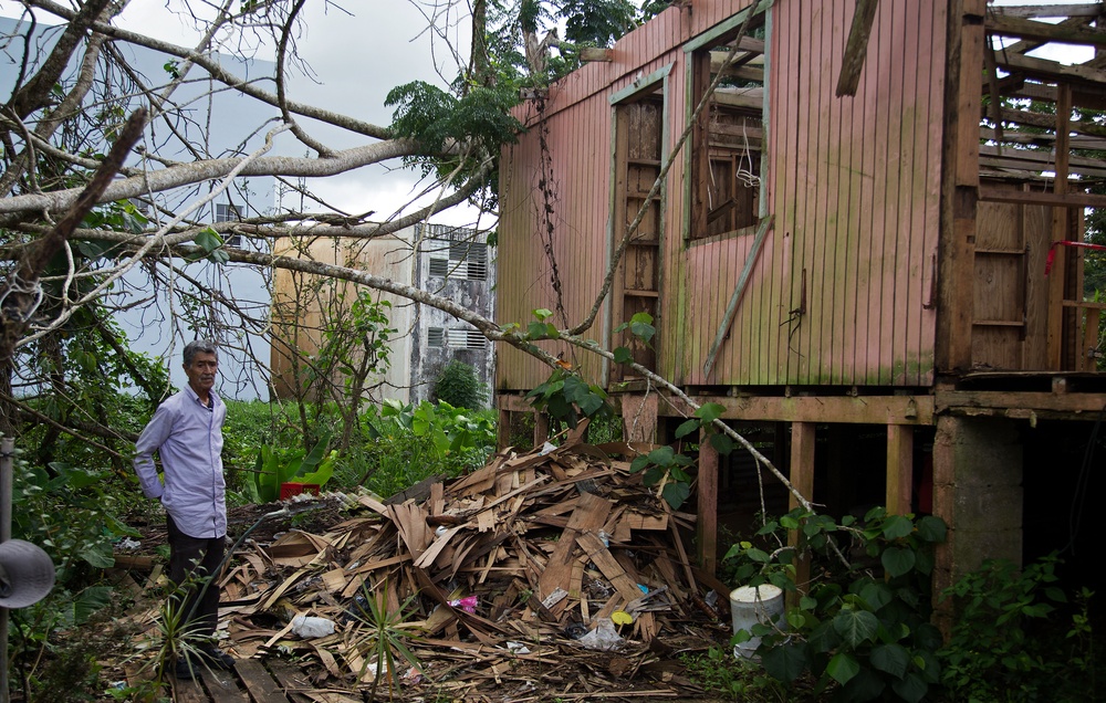 Survivor Stands in Front of His Home