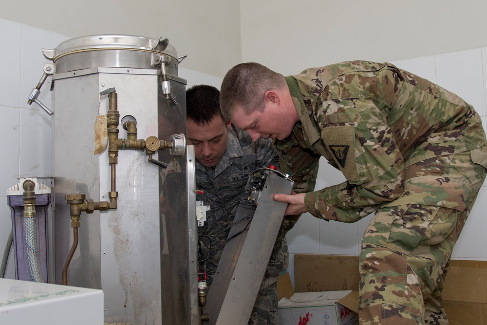 Soldier and Airman Examine Equipment Sterilization Unit
