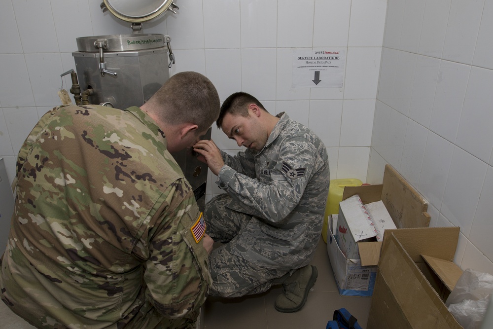 Soldier and Airman Examine Equipment Sterilization Unit