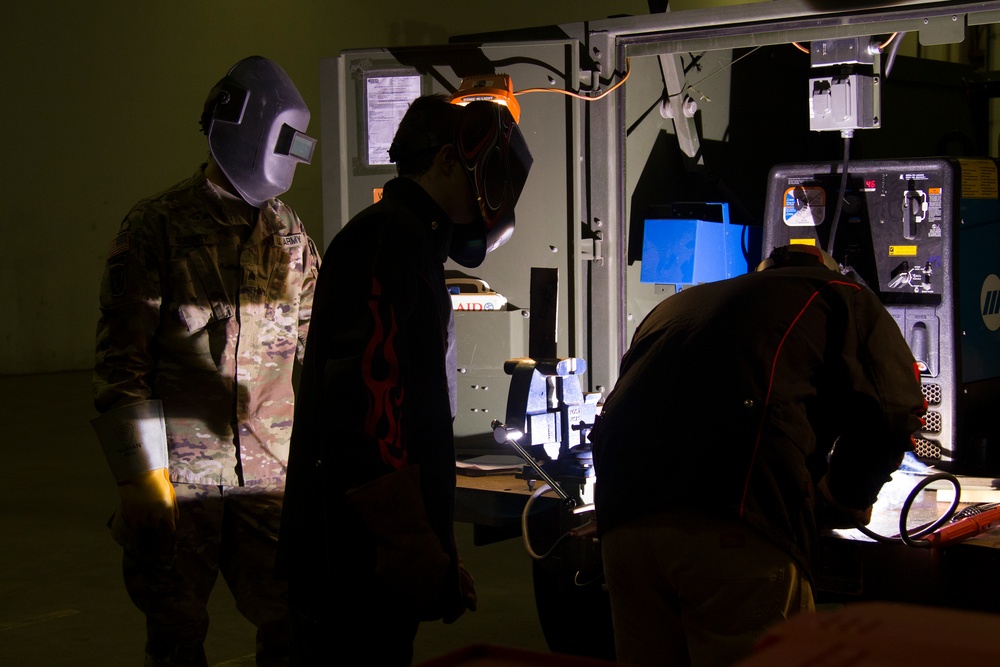 Soldier Observes Students Welding