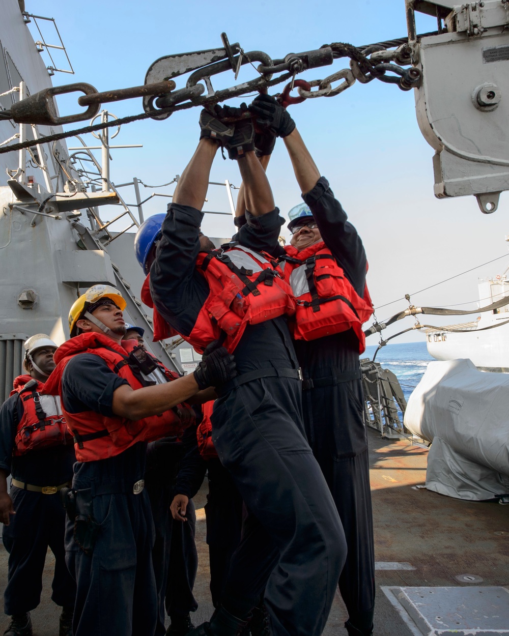 USS Mustin (DDG 89) Sailors prepare to receive supplies from USNS Matthew Perry (T-AKE-9) during a replenishment-at-sea (RAS)