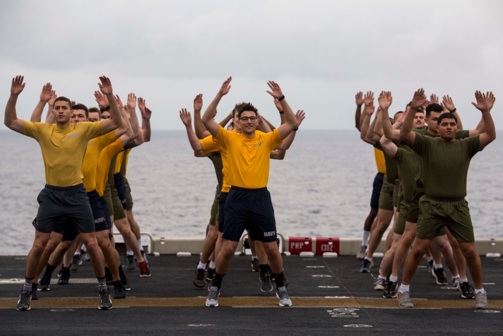 Marines and Sailors PT on the flight deck of the USS Wasp