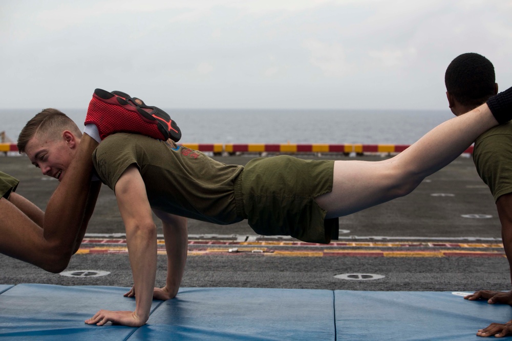 Marines and Sailors PT on the flight deck of the USS Wasp