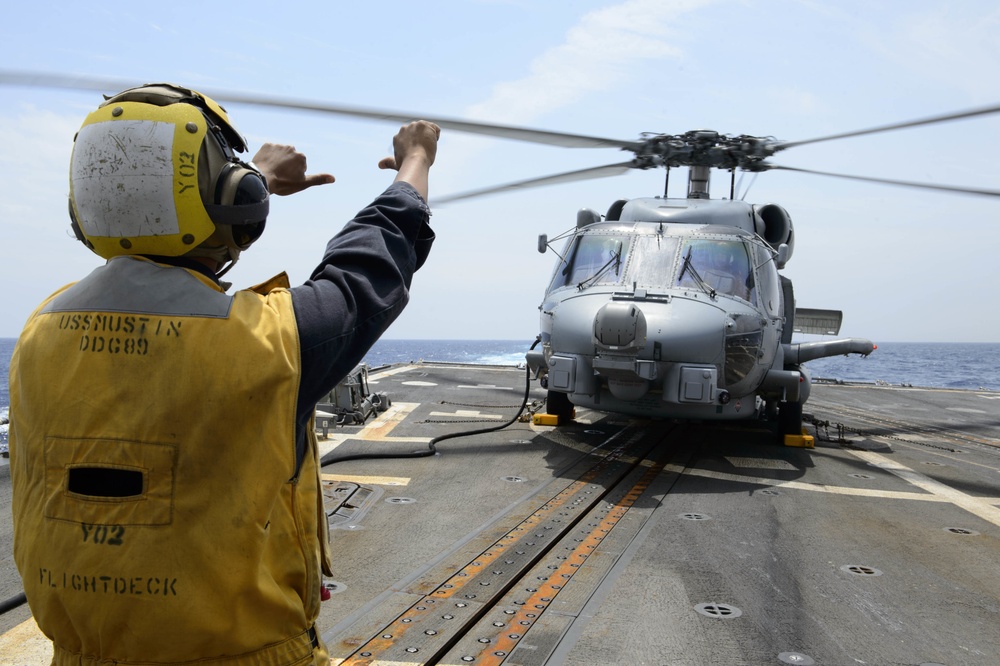 USS Mustin (DDG 89) Sailor signals to HSM 51 Sea Hawk Helicopter during flight quarters