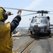 USS Mustin (DDG 89) Sailor signals to HSM 51 Sea Hawk Helicopter during flight quarters