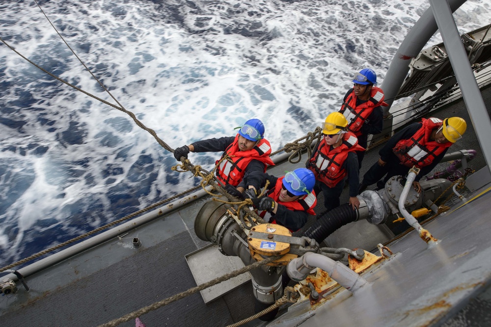 USS Mustin (DDG 89) Sailors prepare to receive fuel during a replenishment-at-sea (RAS) with USNS Matthew Perry (T-AKE-9)
