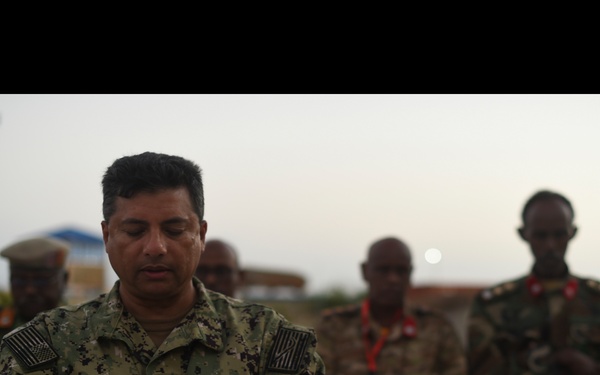 A collage of photographs depicting a military Iftar or religious meal gathering, featuring U.S. Navy and African military personnel. The central image shows a U.S. Navy servicemember with arms crossed in a posture of prayer or reflection. The surrounding images show food preparation, communal dining, and prayer activities shared between multinational military forces.