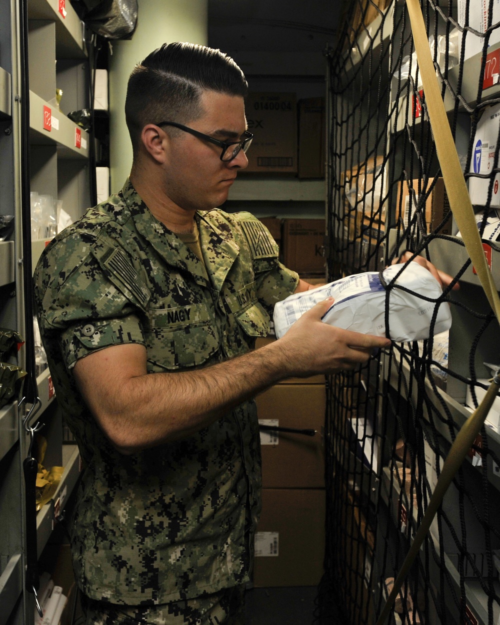 Hospital Corpsman 3rd Class John Nagy retrieves medical supplies from a storeroom during a training evolution in medical department aboard the submarine tender USS Emory S. Land (AS 39)