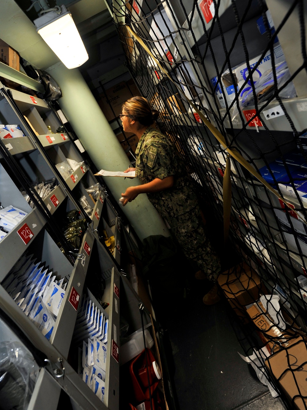 Hospital Corpsman 3rd Class Bryanna Perry searches for supplies in a storeroom during a training evolution in medical department aboard the submarine tender USS Emory S. Land (AS 39)