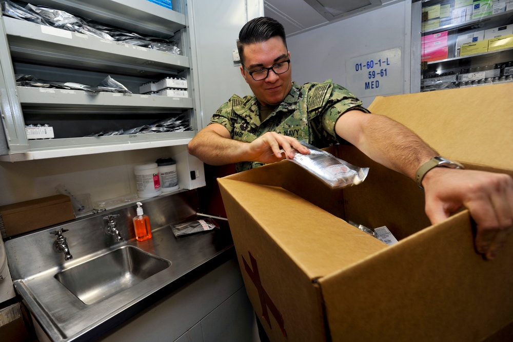 Hospital Corpsman 3rd Class John Nagy puts medical supplies into a box during a training evolution in medical department aboard the submarine tender USS Emory S. Land (AS 39)