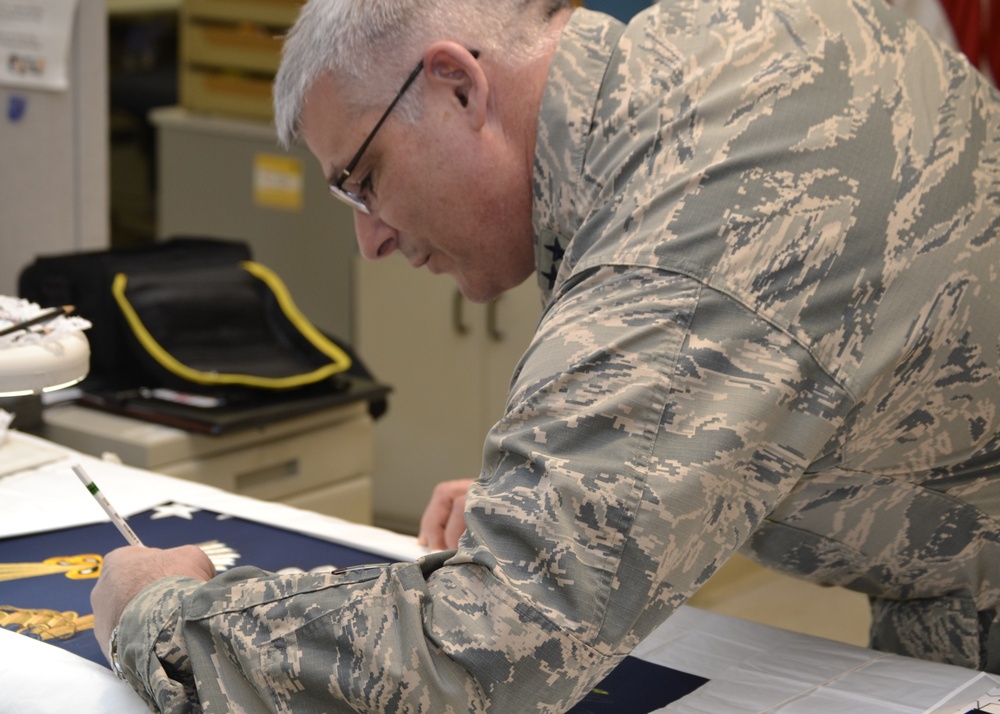 The 53rd Adjutant General of the Pennsylvania National Guard Air Force Maj. Gen. Anthony Carrelli signs a presidential flag being hand-embroidered at DLA Troop Support in Philadelphia April 16.