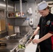 Sailor Serves Prepares Food In Galley