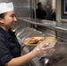 Sailor Serves Food In Galley