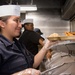 Sailor Serves Food In Galley