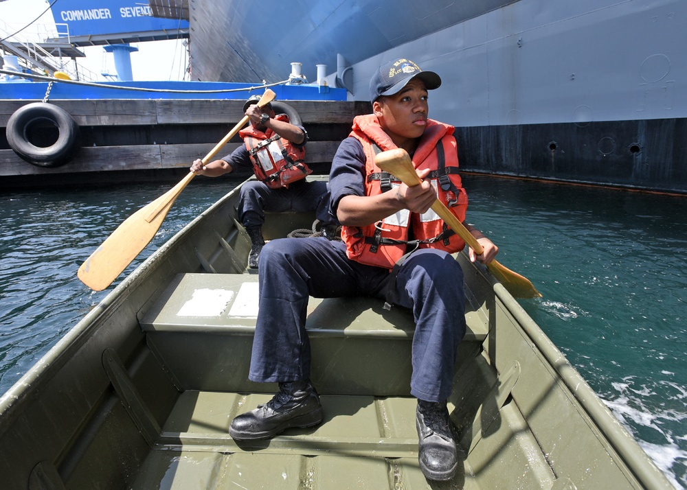 Deck Sailors use a small craft to perform corrosion preventative maintenance on the port side anchor.